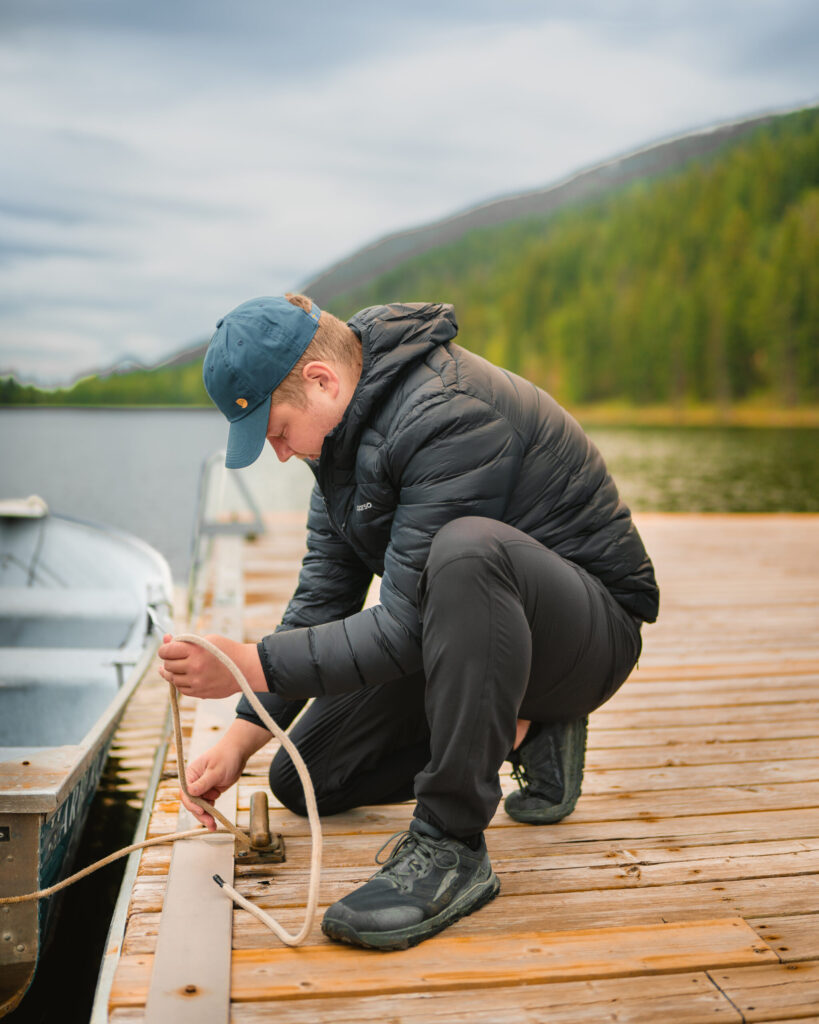 A man kneels on a dock as he ties up a boat at Alpine Meadows Resort in Clearwater, British Columbia