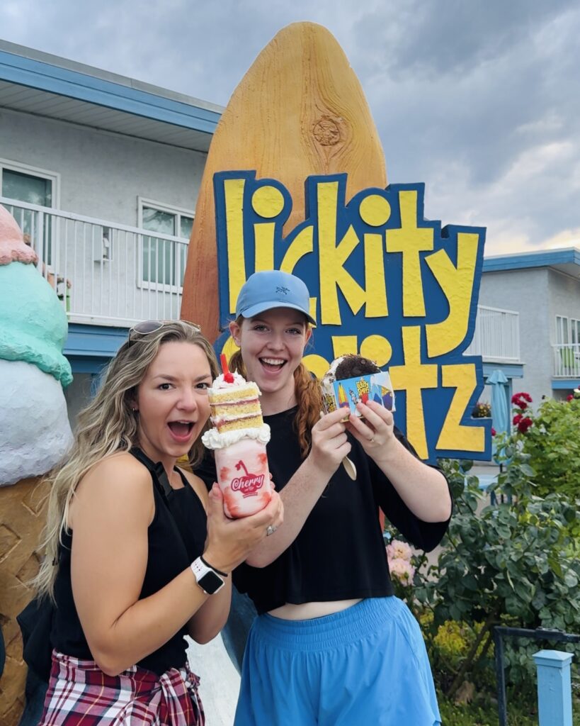 Two girls hold up their large ice cream treats in front of Lickity Splitz in Penticton, British Columbia