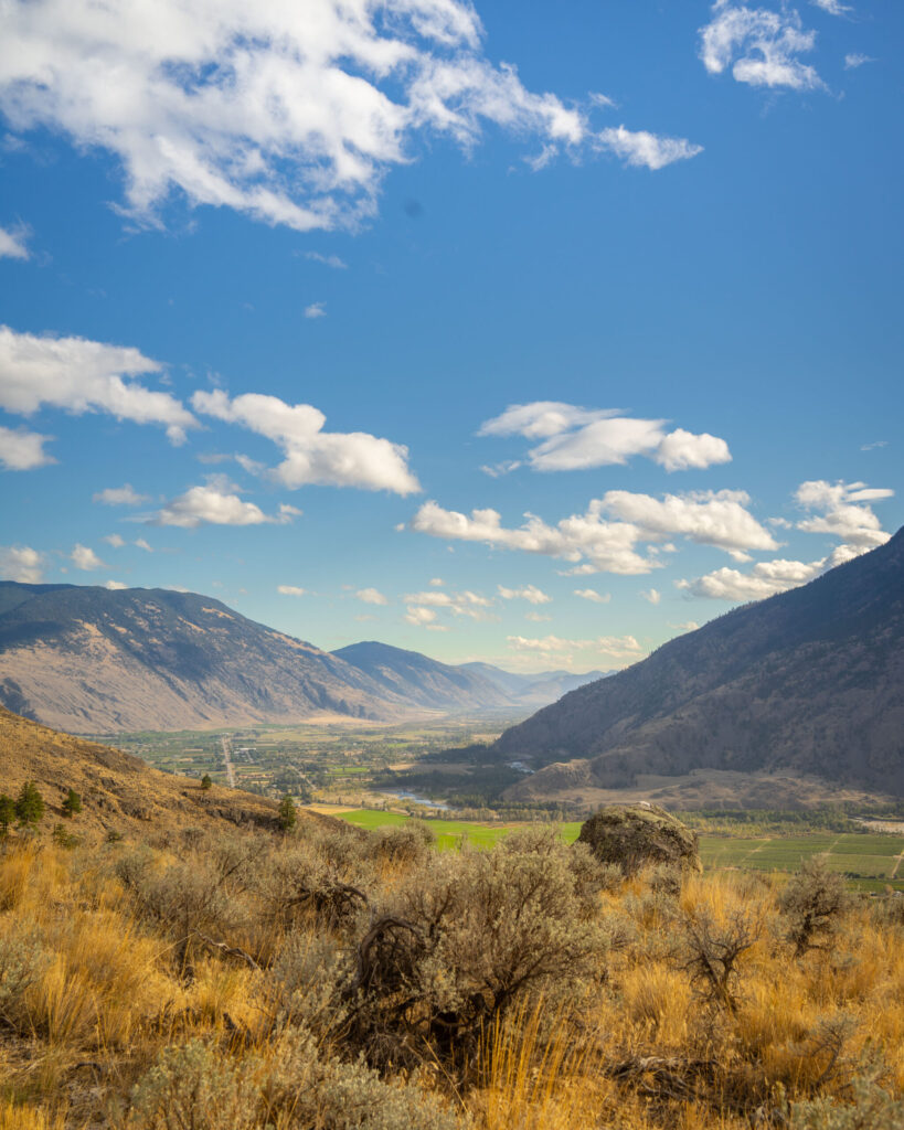 Wide valley view of the Okanagan Valley in British Columbia with mountains, vineyards, and rolling hills. Keremeos and Cawston.
