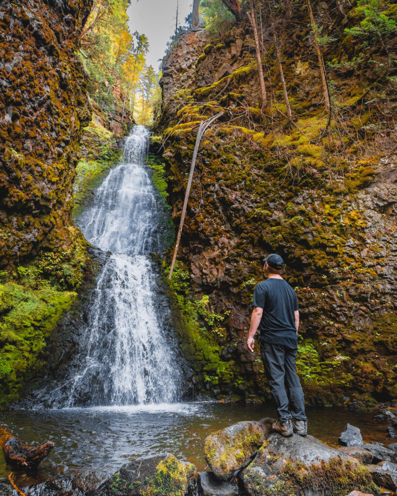 A man stands beside Triple Decker Falls  in Wells Gray Provincial Park British Columbia, looking up in admiration