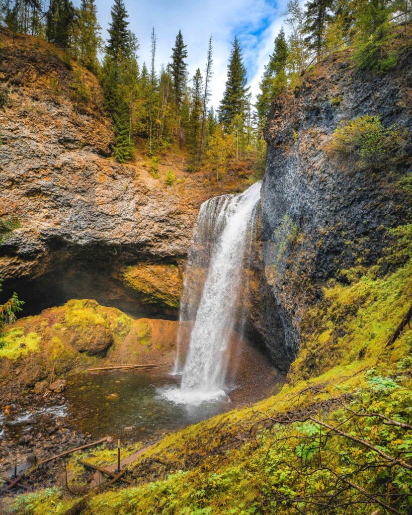 Moul Falls is surrounded by mossy green landscape and volcanic rock  in Wells Gray Provincial Park British Columbia