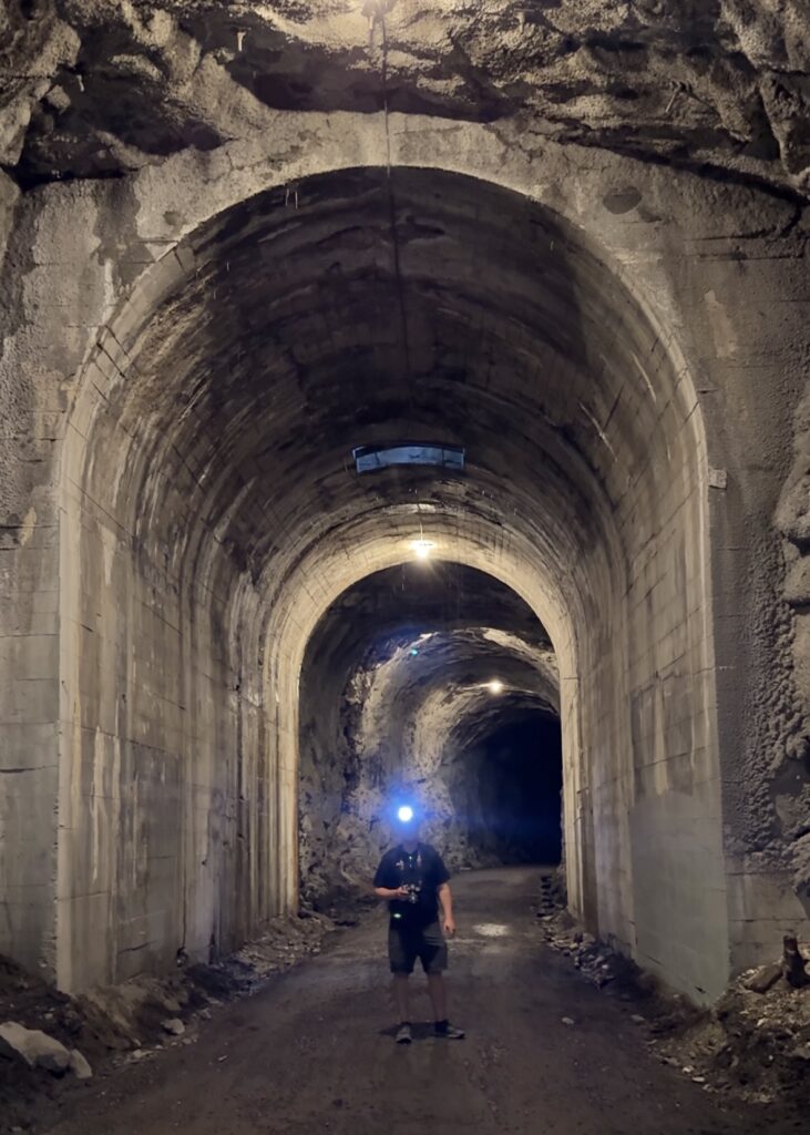 A man stands beneath the Adra Tunnel on the KVR Trail in Naramata, British Columbia. 
