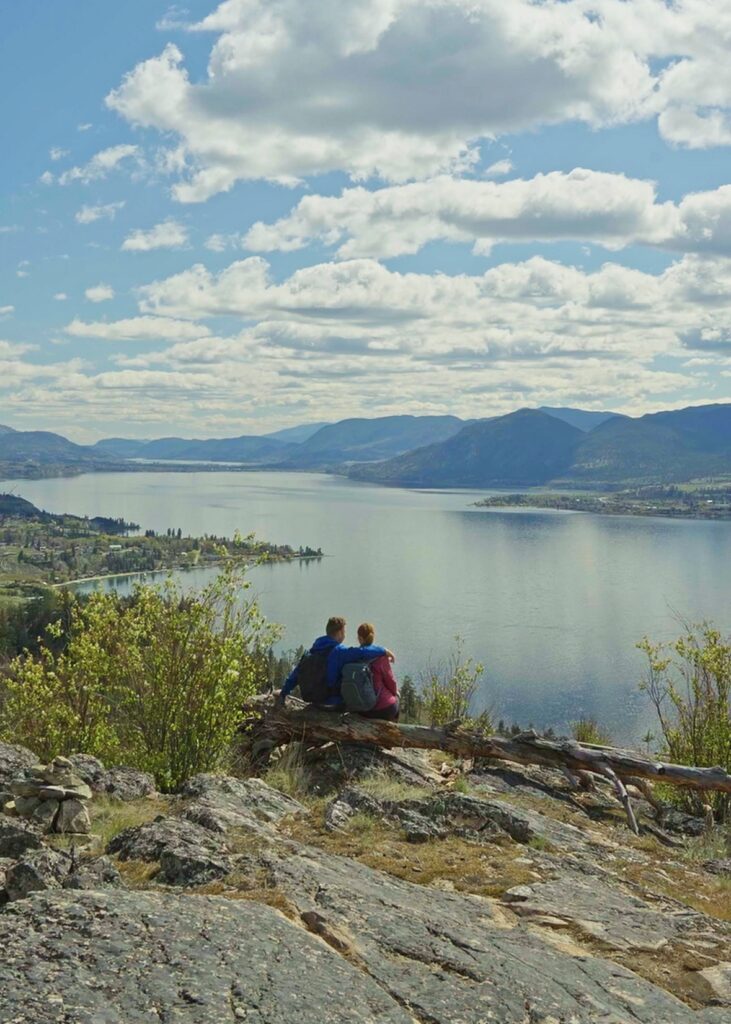 A couple sits looking out towards Okanagan Lake from the Little Tunnel on the KVR Trail in Naramata British Columbia.