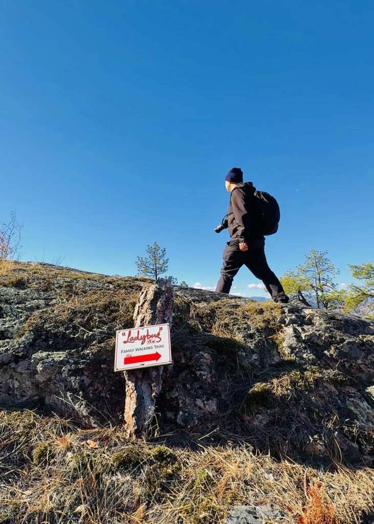 A man hikes by The Ladeybug Trail sign at The Little Tunnel in Naramata British Columbia