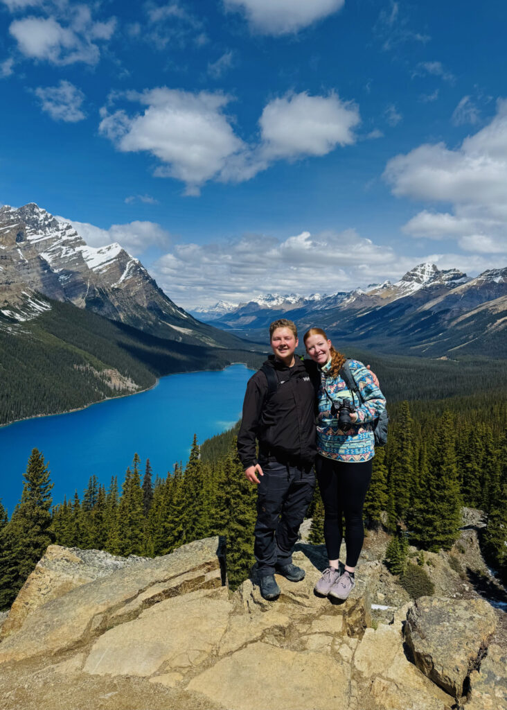 A couple stands on a rock ledge at Peyto Lake in Banff National Park